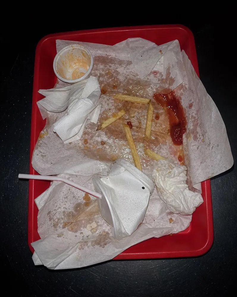 A red tray of crumpled paper and cold fries at the end of a meal