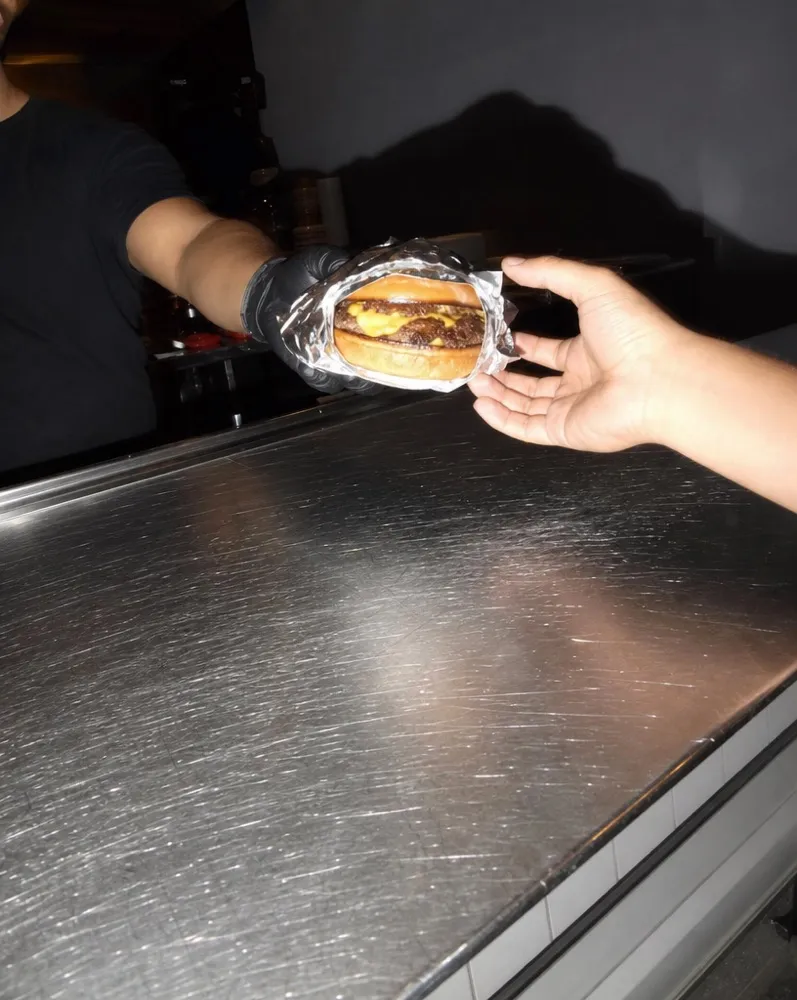 A foil-wrapped burger handed across the counter