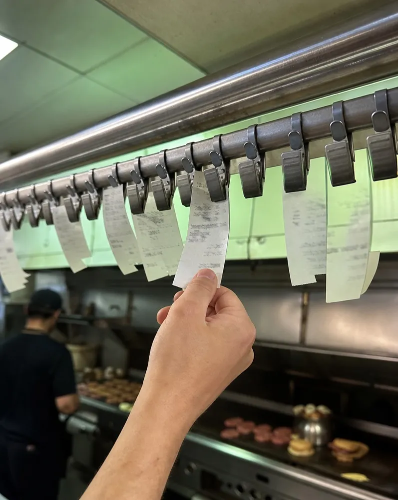 A cook tearing an order ticket off the kitchen rail